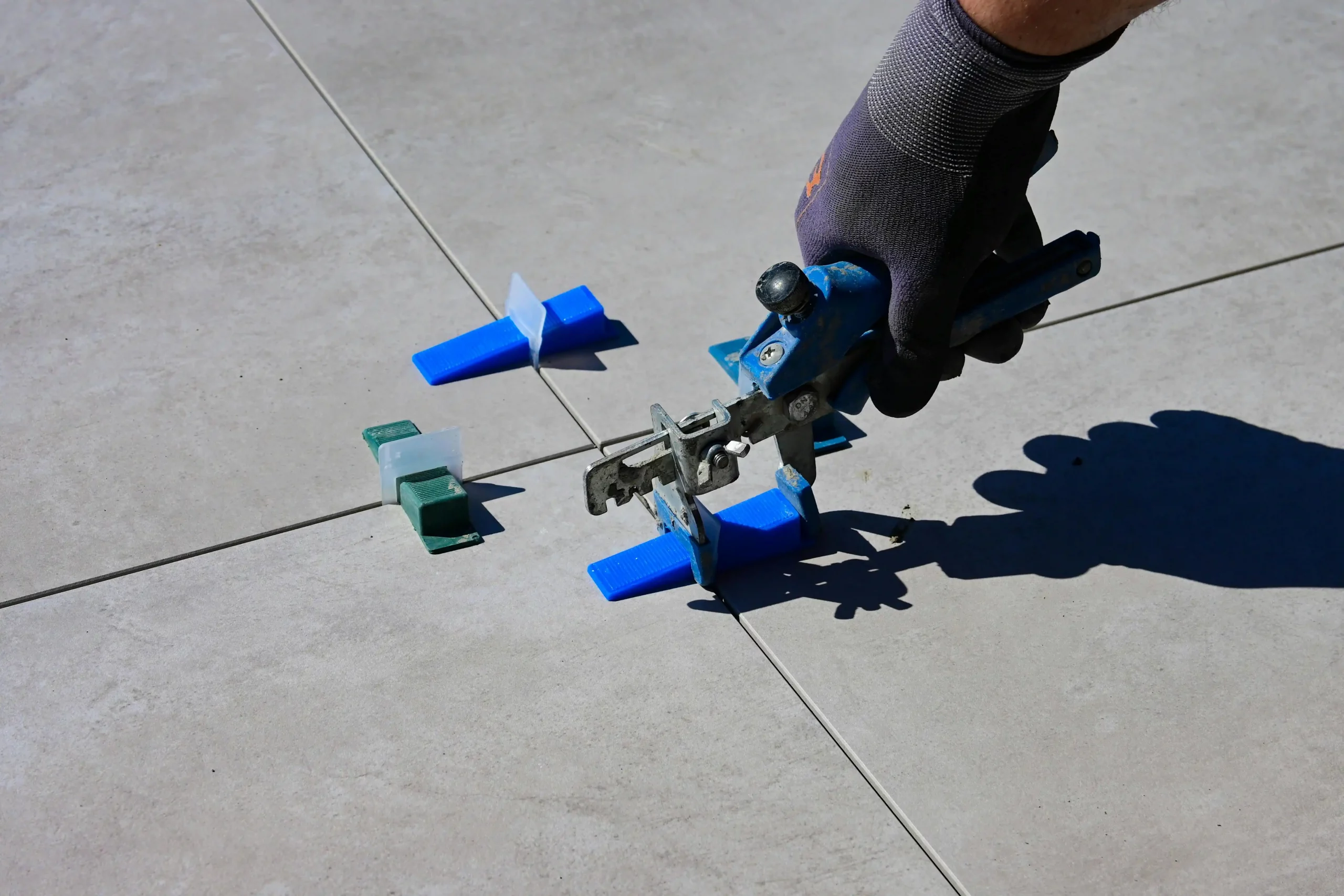 Hand in a glove using a tile levelling tool to set tiles over underfloor heating